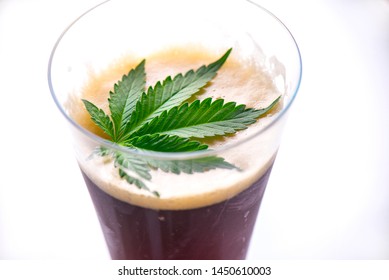 Detail of cold glass of beer with cannabis leaf  isolated over white, marijuana infused beverage concept