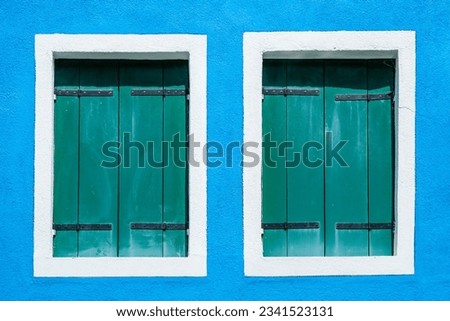 Detail with a colorful house windows with  blue painted wall and wooden shutters in Burano, Italy.