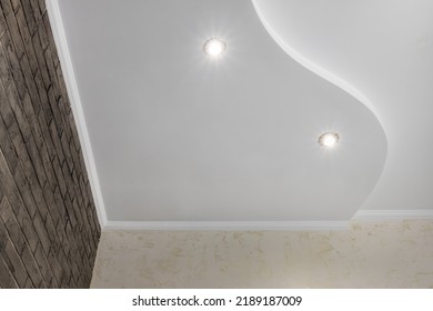 Detail of corner ceiling with intricate crown molding. Suspended ceiling and drywall construction in empty room in apartment or house. Stretch ceiling white and complex shape.