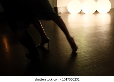 Detail Of A Couples Feet Dancing Tango In A Dark Room, Lit By Three Round Lights