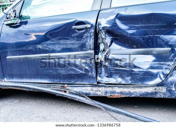 Detail of crashed car after accident, blue metal\
plates on side door\
deformed