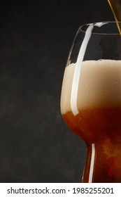 Detail Of Dark Beer With Overflowing Foam Head. Stream Of Dark Stout Pours Into A Beer Glass. Selective Focus