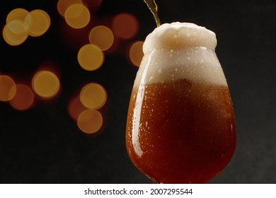Detail Of Dark Beer With Overflowing Foam Head. Stream Of Dark Stout Pours Into A Beer Glass. Selective Focus	