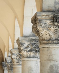 Detail Of An Decorated Or Ornamented Capital Or Chapiter Column Or Pillar In A Row With Others Next To Each Other In A Hall With Arches As Historic And Antique Background Design