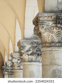 detail of an decorated or ornamented capital or chapiter column or pillar in a row with others next to each other in a hall with arches as historic and antique background design - Shutterstock ID 2354024331