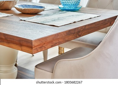 Detail of dinner table made of solid walnut wood on massive legs and served with plates. Close-up