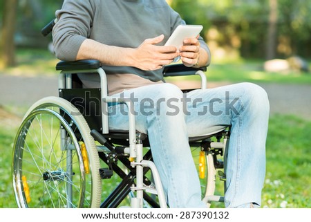 Detail of a disabled man using a tablet in a park