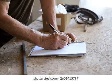 
Detail of an elderly man's hands taking notes in a workshop