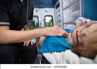 Detail of EMT worker listening to heart of senior woman patient in ambulance - Powered by Shutterstock