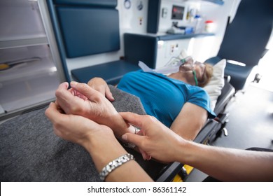 Detail Of EMT Worker Measuring Pulse On Senior Woman Patient In Ambulance