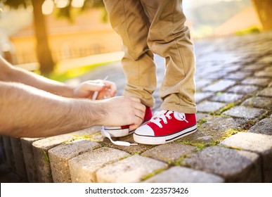 Detail Of Father's Hands Tying His Little Son's Shoes