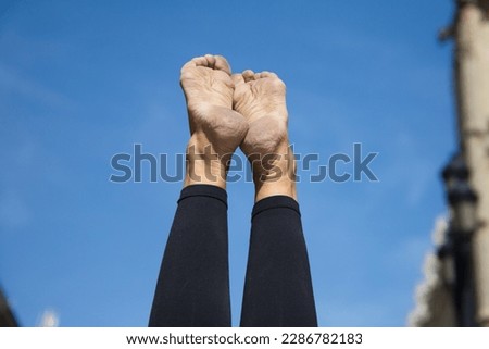 Detail of feet and legs of woman doing yoga in the street. The photo is taken from below and you can see in the background the blue sky and the gothic cathedral of Seville. Health and relaxation.