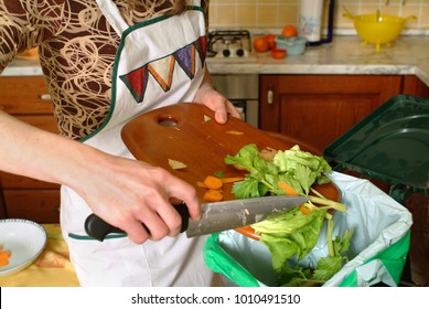 Detail of a female hand throwing organic waste in a proper bin with kitchen in the background. - Powered by Shutterstock