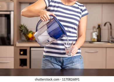 Detail Of Female Hands Holding A Filtered Water Pitcher And Pouring Filtered Water Into A Glass