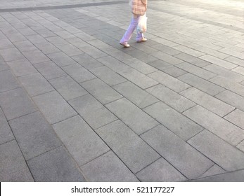Detail of a female worker walking on concrete brick floor on the street near sunset