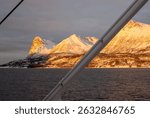 Detail of a ferry from Stornes to island Grytoya. Mountains with snow in the light of sunrise on the horizon. Cloudy sky. Norwegian sea. Arctic late autumn. Stornes - Grytoya, Norway.