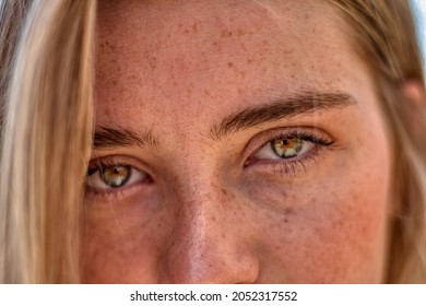 Detail of the freckled face of a blonde girl with green eyes