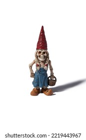 Detail Front Shot Of A Designer Figurine Of A Skeleton Of A Dwarf Woman In A Red Hat And A Blue Dress With A Basket In Hand. The Original Handmade Statuette Is Isolated On The White Background.      