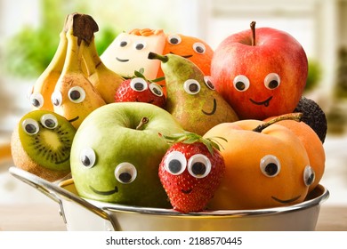 Detail Of A Fruit Bowl Full Of Fruit With Eyes And A Mouth On The Bench In A Bright Kitchen. Fruits And Vegetables Child Healthy Eating Concept.