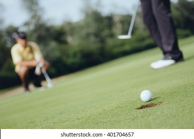 Detail From Game Of Golf. Focus On Ball, Golfers In Background, Toned Image