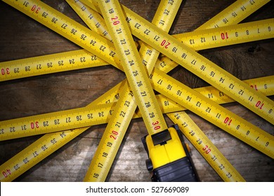 Detail of a group of tape measures on a wooden table with dark shadows