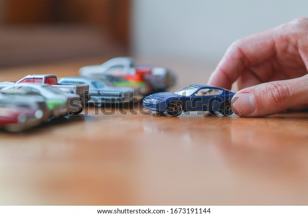 detail of a hand\
grabbing small toy cars