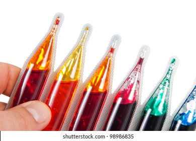 Detail Of A Hand Holding Food Dye In Different Colors Over A White Background