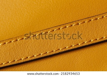 Detail of handbag with stitching, genuine leather of bright yellow color. Texture and fashionable modern background, copy space