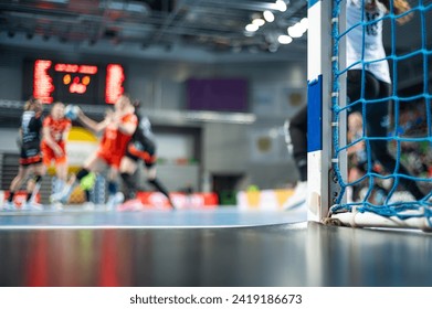 Detail of handball goal post with net and game in the background. - Powered by Shutterstock