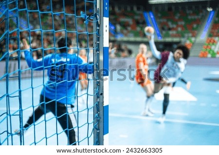 Detail of handball goal post with net and game in the background.
