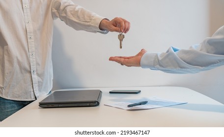 Detail Of The Hands Of The Agent Giving The Keys To The Buyer, In The Real Estate Agency. Horizontal Photography With Copy Space.