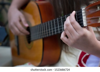 detail of the hands of a girls playing traditional chilean cueca in an acustic guitar