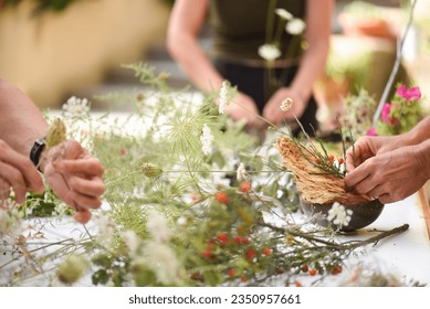 Detail of hands making flower arrangement, outdoor ikebana workshop, different flower arrangements in progress. - Powered by Shutterstock