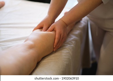 Detail of hands massaging human calf muscle.Therapist applying pressure on female leg. Hands of massage therapist massaging legs of young woman in spa salon. Body care in spa salon for young woman. - Shutterstock ID 1902063910