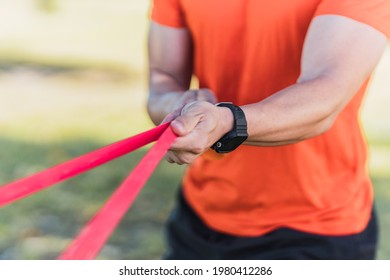 Detail Of The Hands Of A Sportsman Exercising With An Elastic Band While Stretching It Outdoors