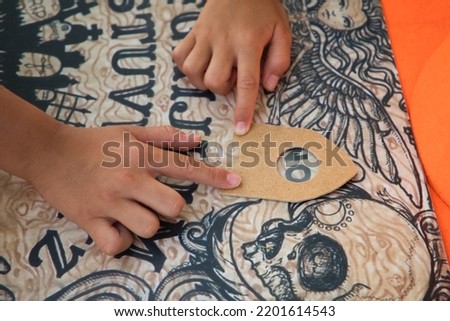 Detail of the hands of two children doing the ouija board in the park. Happy halloween. Trick or treat. 31st October.