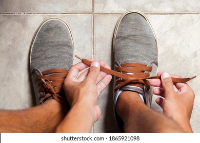 Detail Of The Hands Of A Young Brazilian Man Tying The Tennis Shoe To Practice Walking In The Neighborhood. Footwear Concept. Sport Concept.