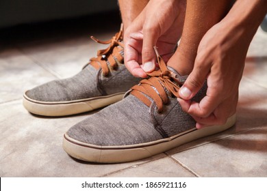 Detail Of The Hands Of A Young Brazilian Man Tying The Tennis Shoe To Practice Walking In The Neighborhood. Footwear Concept. Sport Concept.