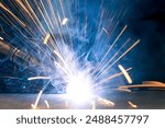 Detail of heavy industry manufacturing, sparks come out of a metal working welder.