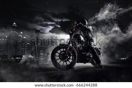 Detail of high power motorcycle chopper with man rider at night. Modern city of Dubai and fog with backlights on background.