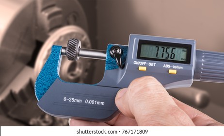 Detail of human hand with digital micrometer. Accurate measurement of knurling tool with a lathe in the background.