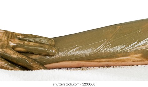 A Detail Image Of A Sea Mud Full Body Wrap At A Luxury Spa Being Applied To The Arm, With Motion Blur On The Hand Applying The Mud Pack.