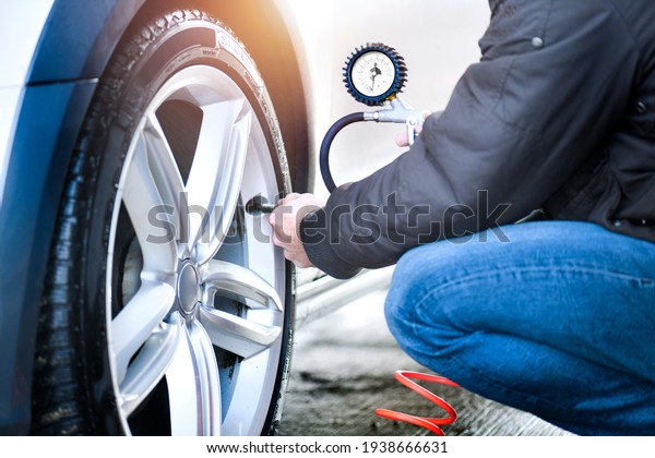Detail of inflating tire and checking air\
pressure use gauge in mechanics hands.\

