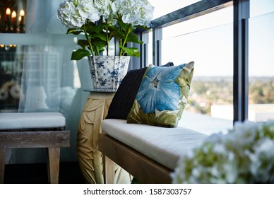 Detail Of An Inner City Apartment Balcony With Settees, Cushions, Hydrangea Flowers In Plant Pot And Candle In The Background