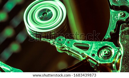 Detail of the inside of a hard disk with the reading head in operation, green light image