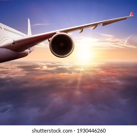 Detail of jetplane wing flying above clouds in sunset. Beautiful sunset scenery, transportation and fast travel concept.