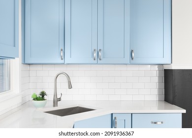 Detail Of A Kitchen With Light Blue Cabinets, White Granite Countertop, Subway Tile Backsplash, And A Light Hanging Above A Window.