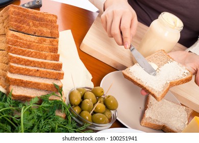 Detail Of Kitchen Table And Female Hands Spreading Mayonnaise Preparing Sandwich.