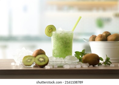 Detail of kiwi soft drink with a lot of ice on a wooden kitchen bench with fruit and a bowl with ice around it. Front view. Horizontal composition. - Shutterstock ID 2161108789