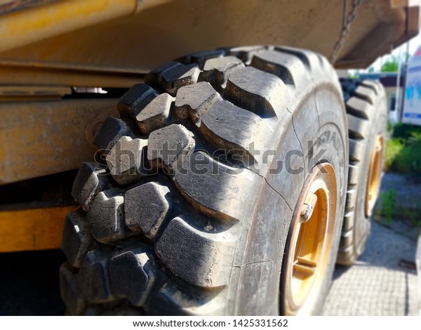 Detail of large tyre big wheels of heavy truck.\
Heavy duty vehicle wheel detail. Tire structure on large yellow\
working lorry.